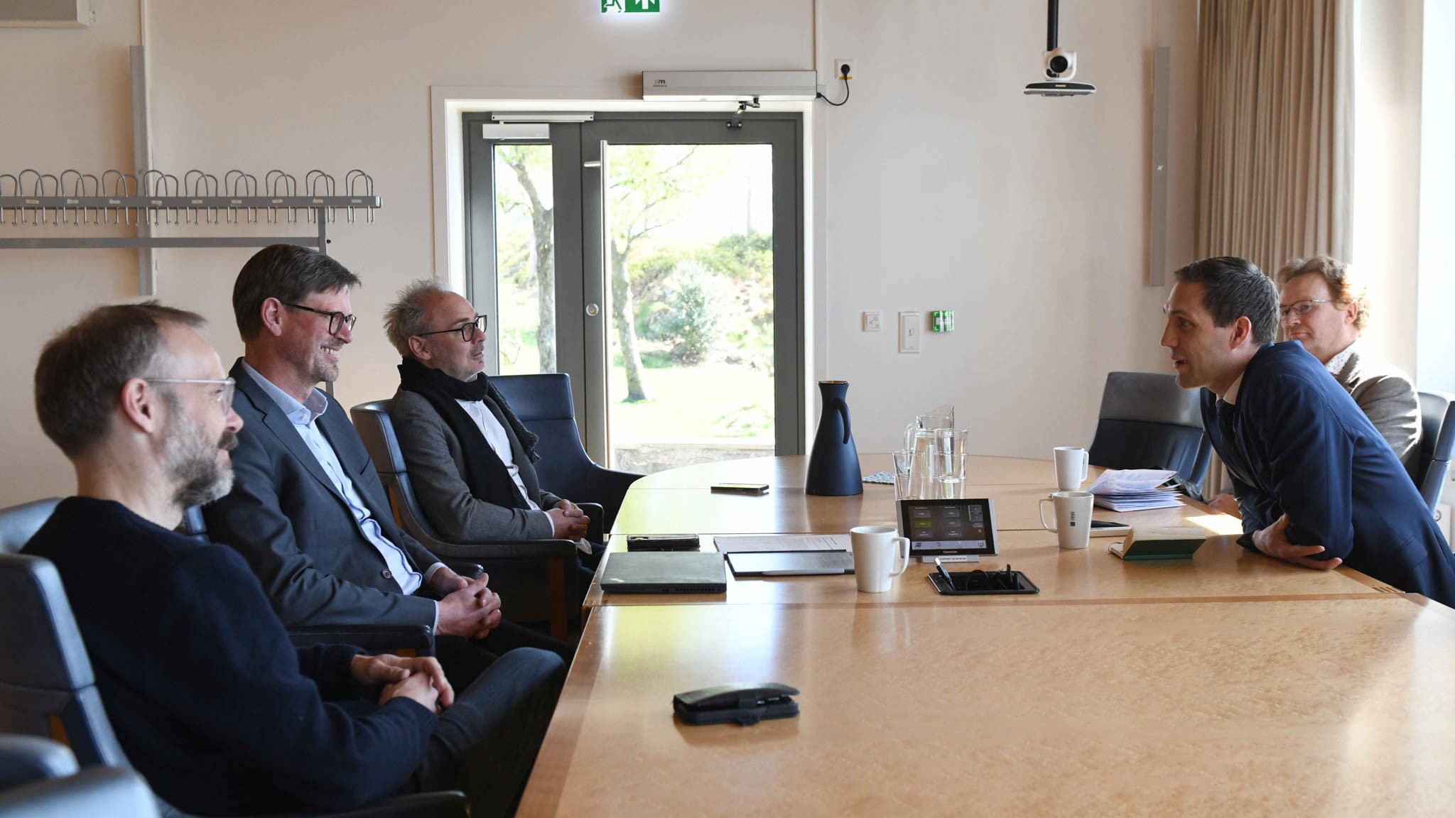 Five people having a meeting, talking around a table