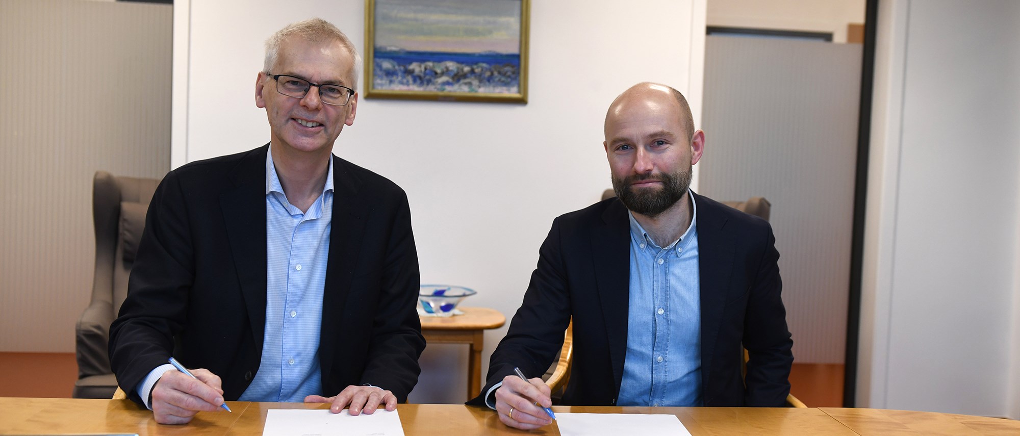 Bilde av NHH-rektor Øystein Thøgersen og Jostein Hole Kobbeltvedt i Raftostiftelsen som signerer samarbeidsavtale. Foto: Hallvard Lyssand
