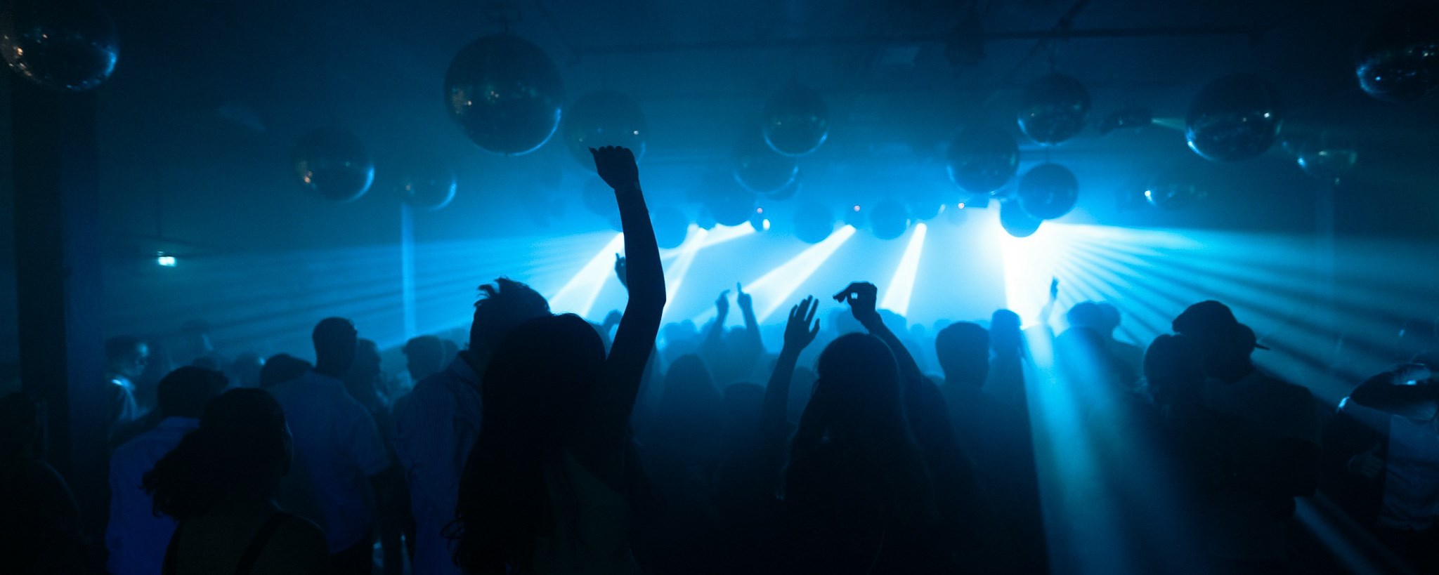 people partying and dancing, blue lights from the stage