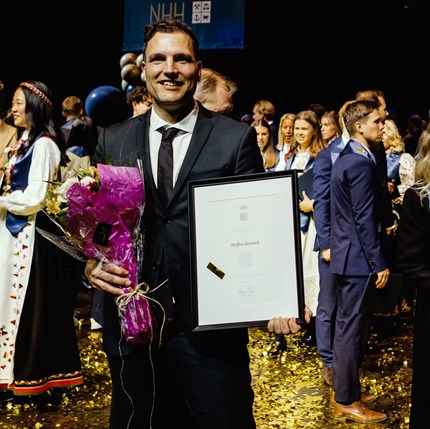 Steffen on stage with the diploma and flowers