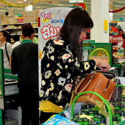 Customer at checkout counter in Tesco store in Thailand.