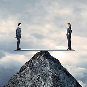 Two people standing on a seesaw at the top of a mountain and balancing