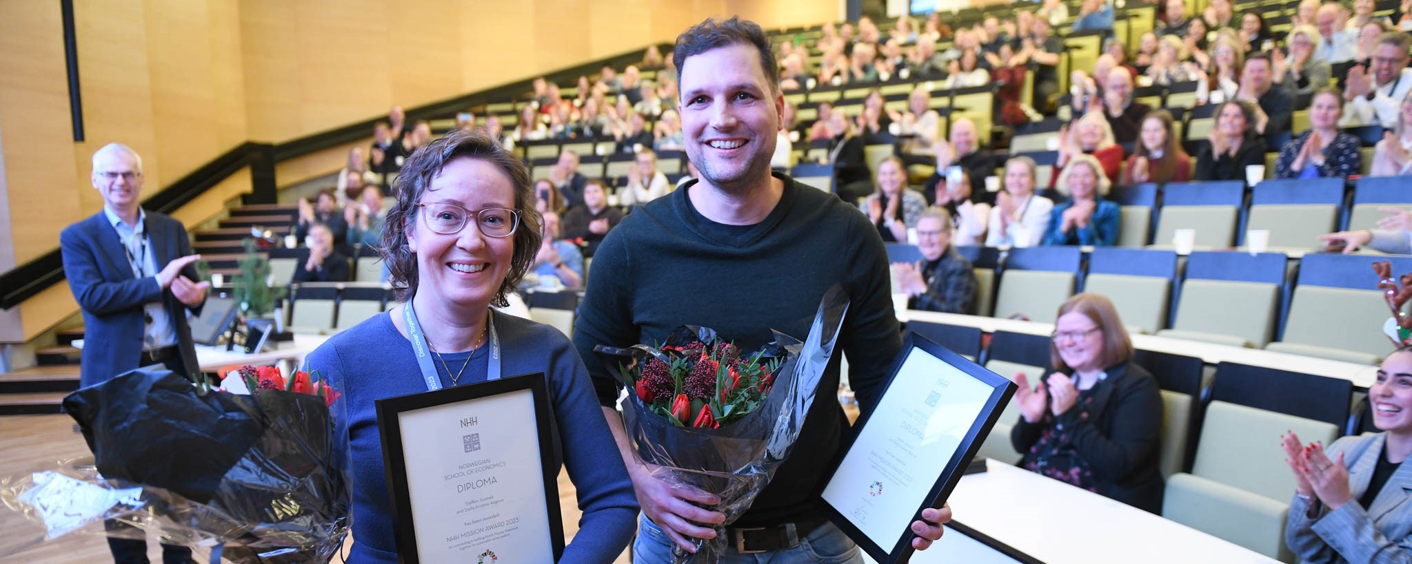 Stella and Steffen in front of the audience after receiving flowers and diploma from rector.  