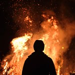 A black silhouette looking at a fire. Photo by Adam Wilson on Unsplash