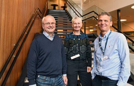 Three people standing in the staircase outside the conference room